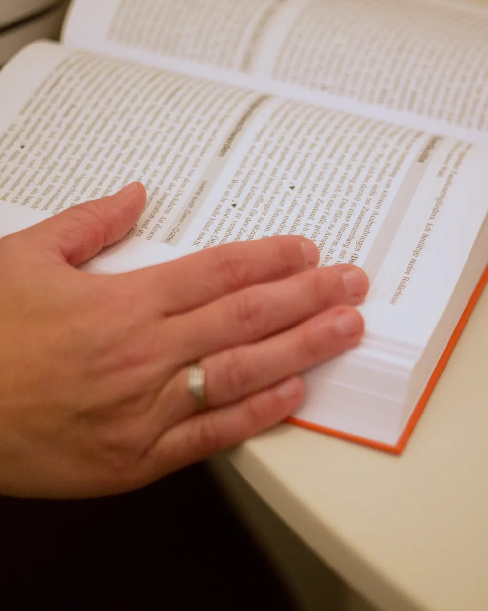 Christianes Hand mit Ring liegt auf einem aufgeschlagenen Buch.